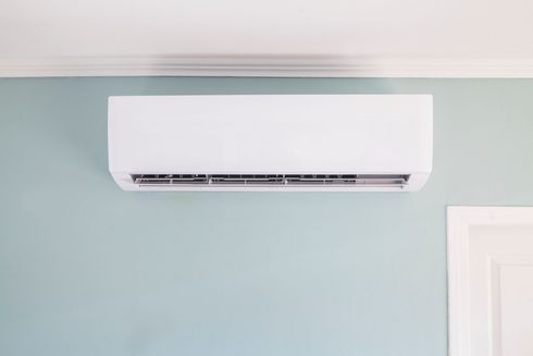 Condizionatore d'aria bianco senza condotti montato su una parete azzurra.