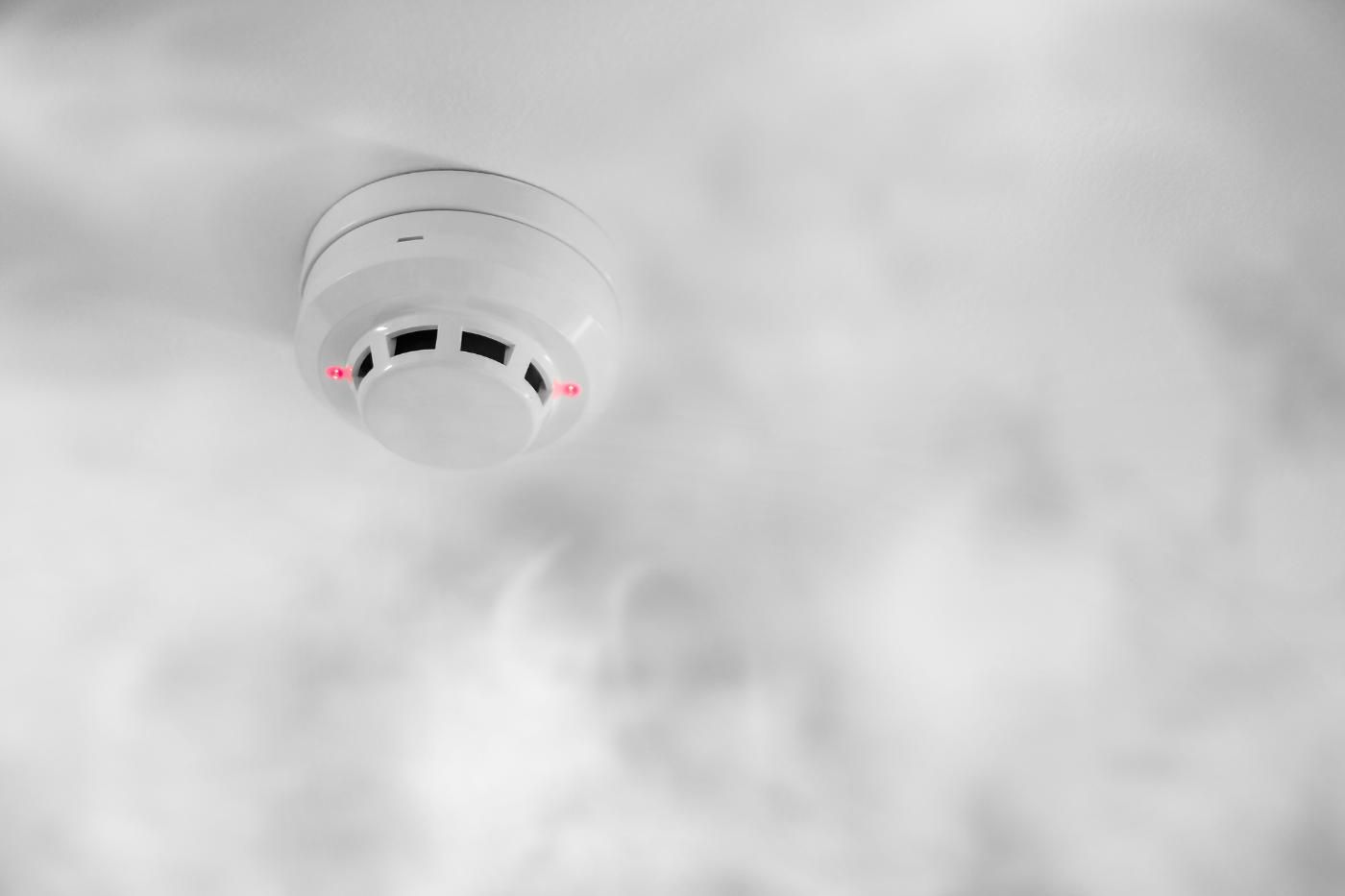 Un irrigatore antincendio spruzza acqua da un tubo rosso in un ambiente industriale.