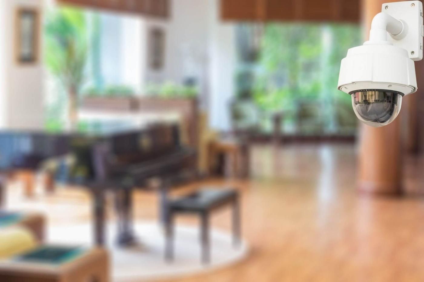 Telecamera di sicurezza in una hall, con vista su un pianoforte e una zona salotto, con sfondo sfocato.