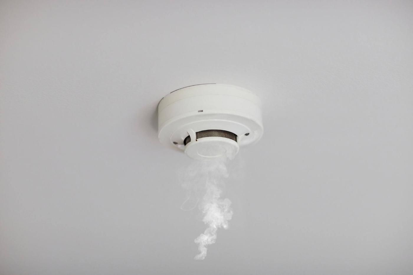 Testina di un irrigatore antincendio che spruzza acqua; tubo rosso in un ambiente industriale.