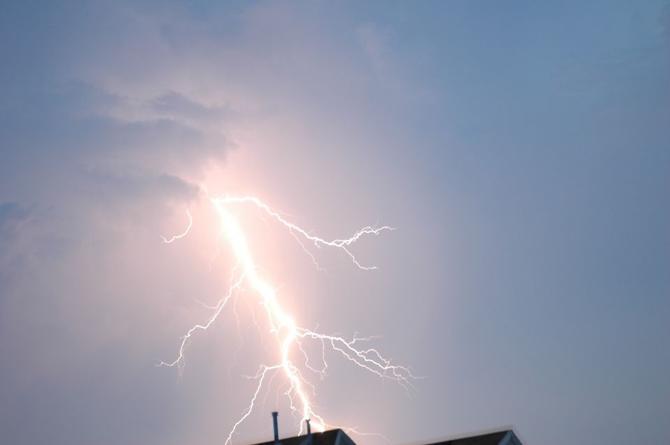 Un fulmine colpisce un edificio durante un temporale: è bianco e luminoso sullo sfondo di un cielo scuro.