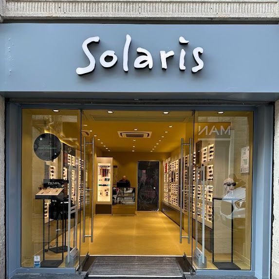Negozio di occhiali Solaris con porte in vetro, espositori all'interno e il nome del negozio scritto in bianco sopra.