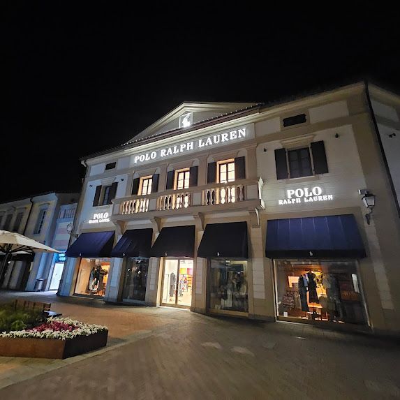 Negozio Polo Ralph Lauren di notte, edificio illuminato con tende da sole e insegne, vista esterna.