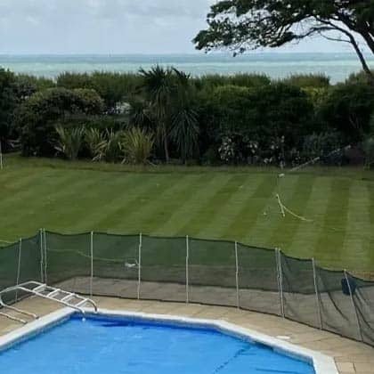 A coastal garden with a well maintained lawn and a swimming pool