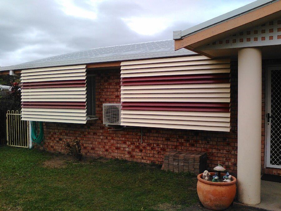Red & Cream Aluminum Awnings In A Brick House