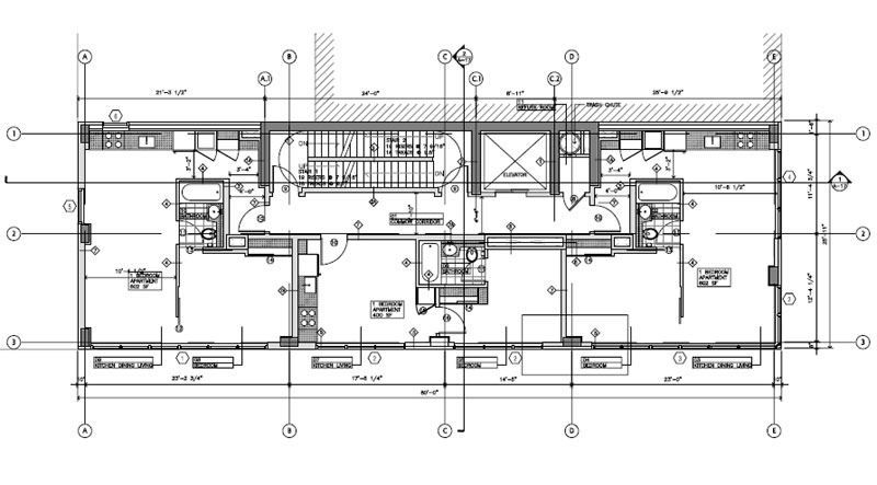 Modern home with a dark gray exterior, large windows, and a sloping roof, set in a wooded area.