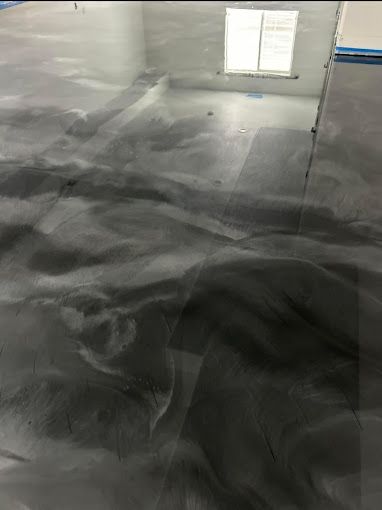 Metallic epoxy floor with flowing black, gray, and silver swirls; reflecting light.