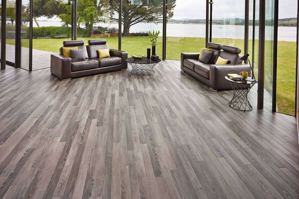 Living room with gray wood floor, leather sofas, and lake view.