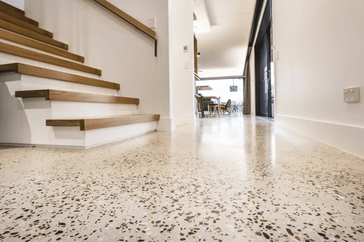 Polished concrete floor in a modern home hallway, with wooden stairs and white walls.