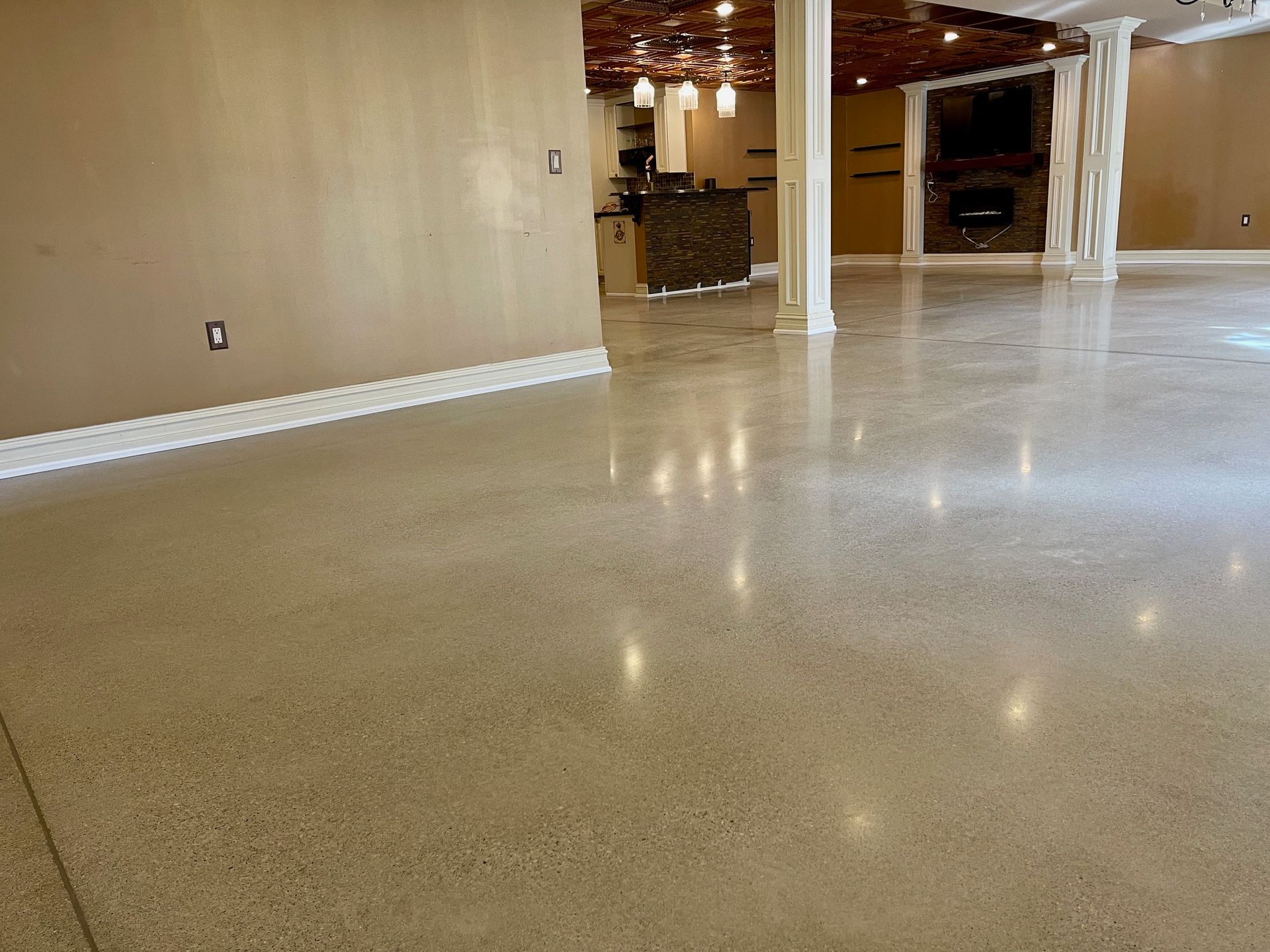 Polished concrete floor reflecting light in an open space with tan walls and a column.
