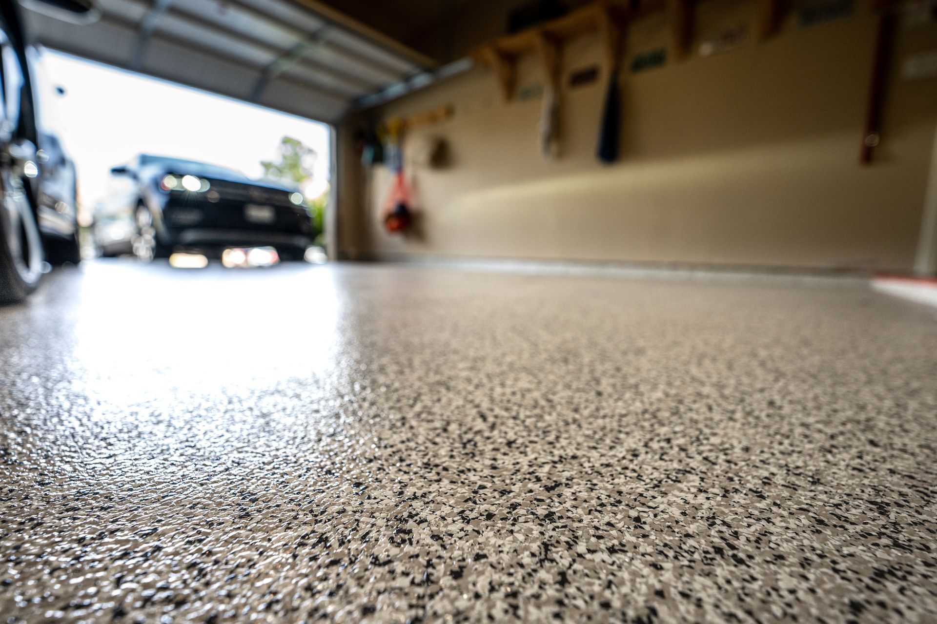Close-up of a speckled epoxy garage floor, with a car parked in the background.