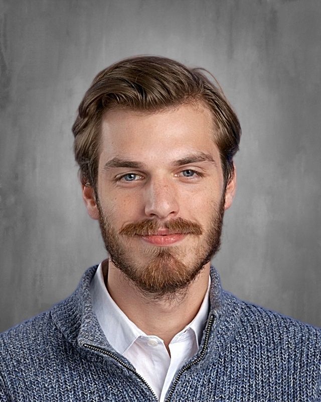 Young man in a blazer and white shirt, with blonde hair and a goatee, looking at the viewer.