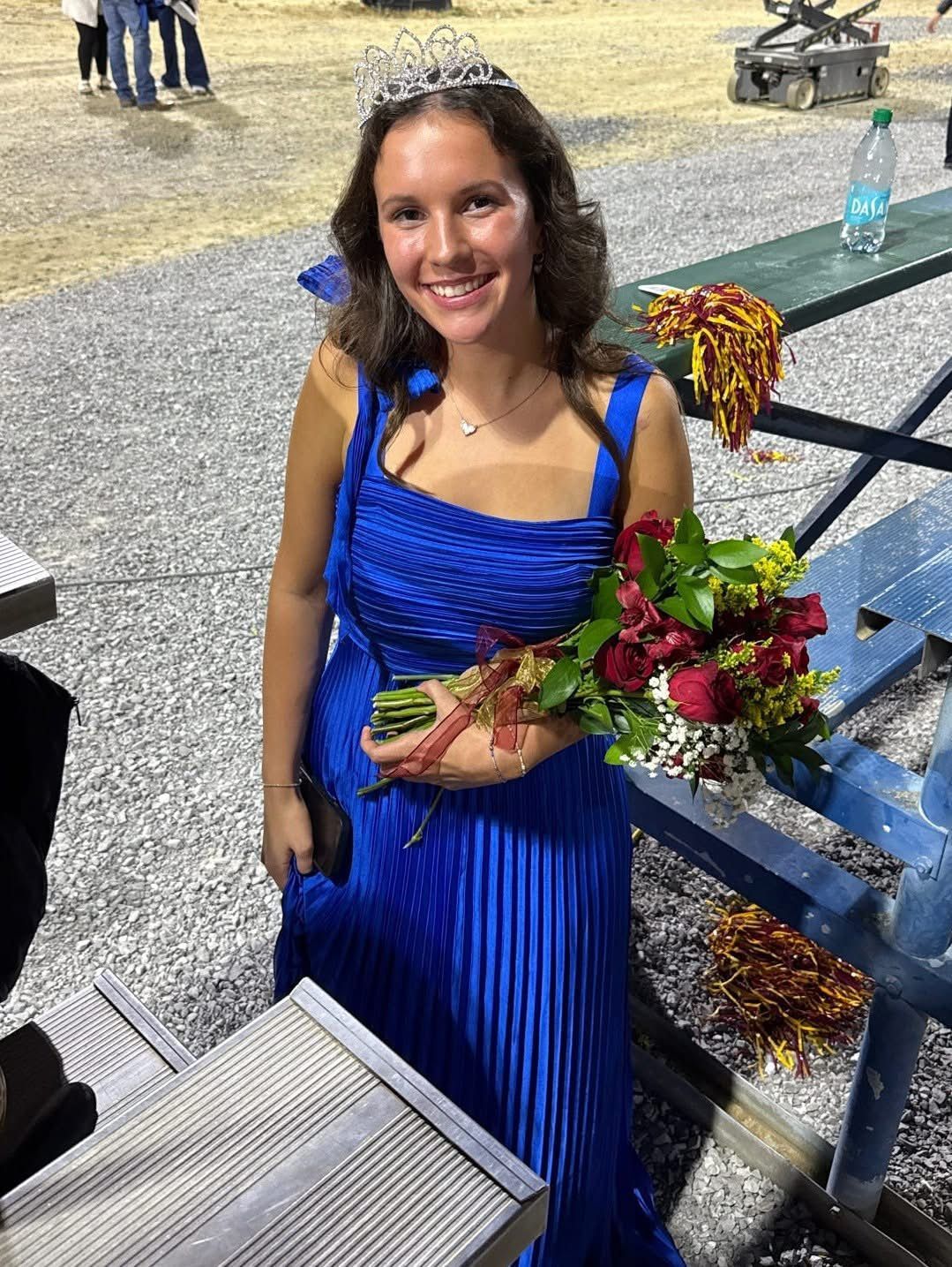 Three young women lying on grass, smiling, wearing casual clothes.