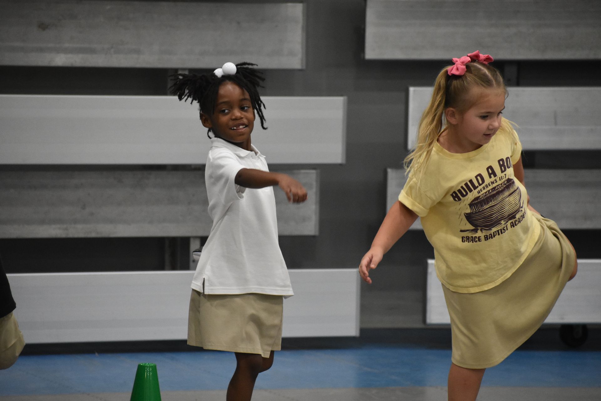 Two young girls dancing in a school gym. One is African American, the other Caucasian.