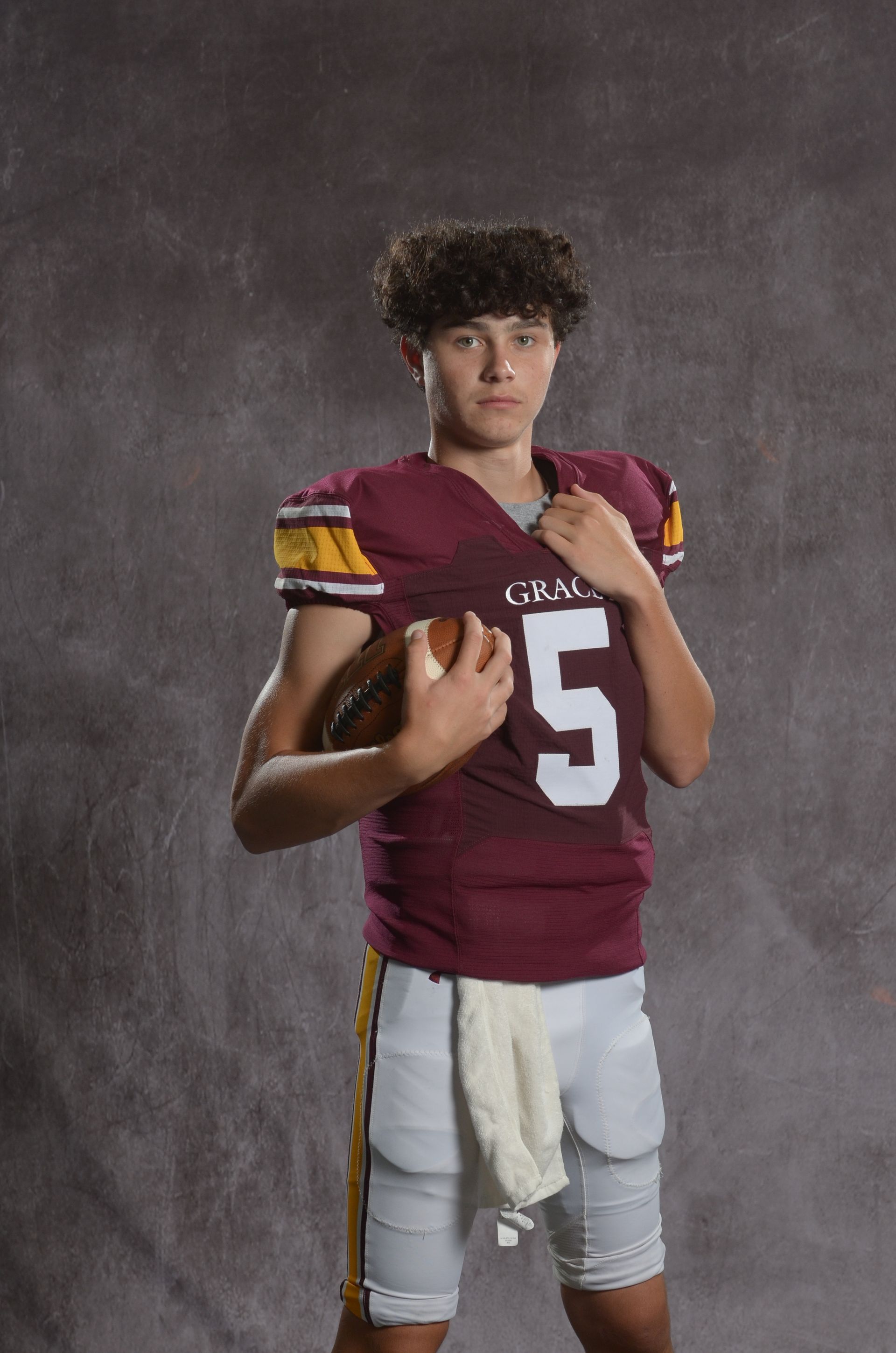 A maroon eagle head logo with a yellow beak on a white background.