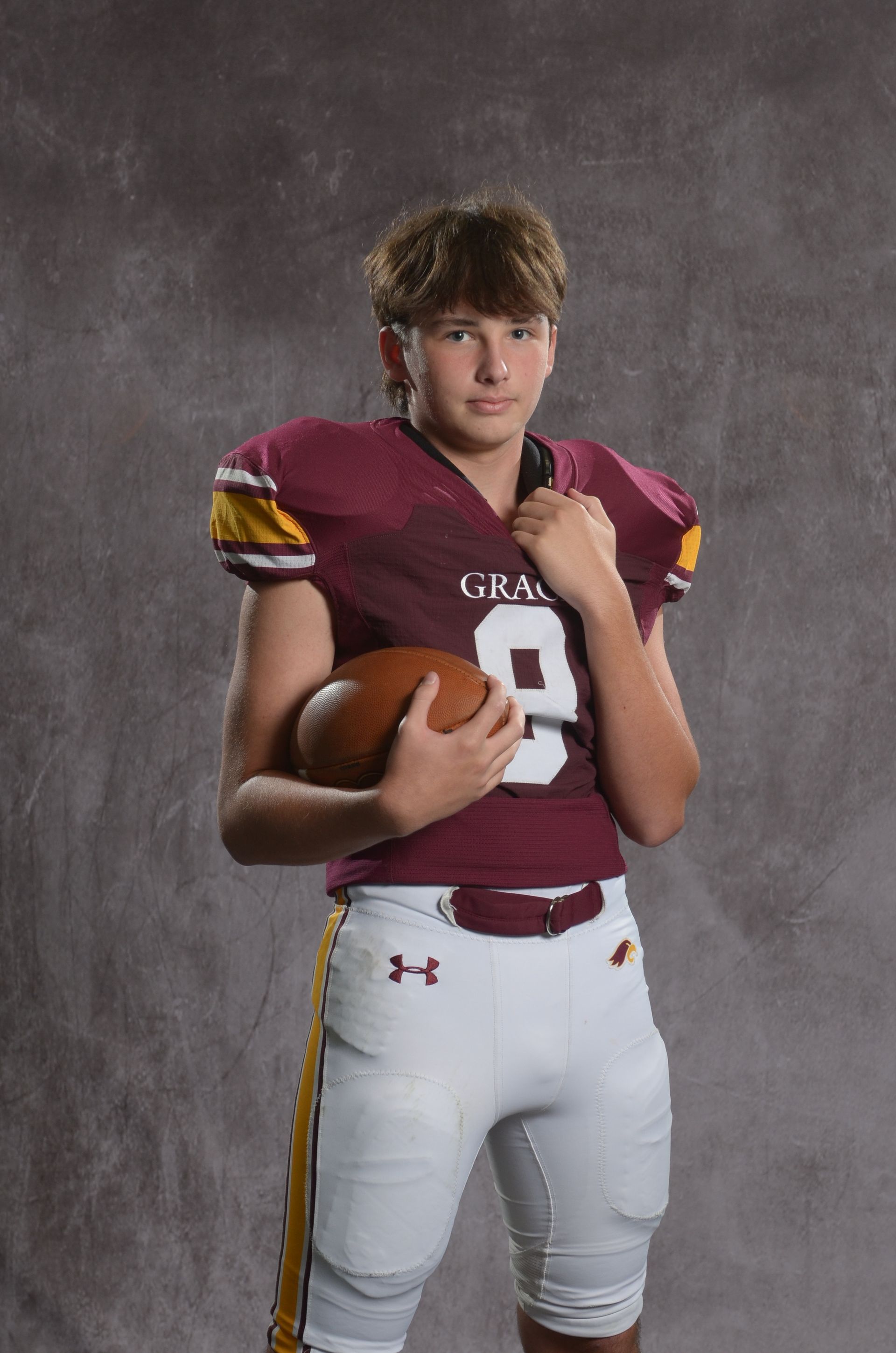 A maroon eagle head logo with a yellow beak on a white background.