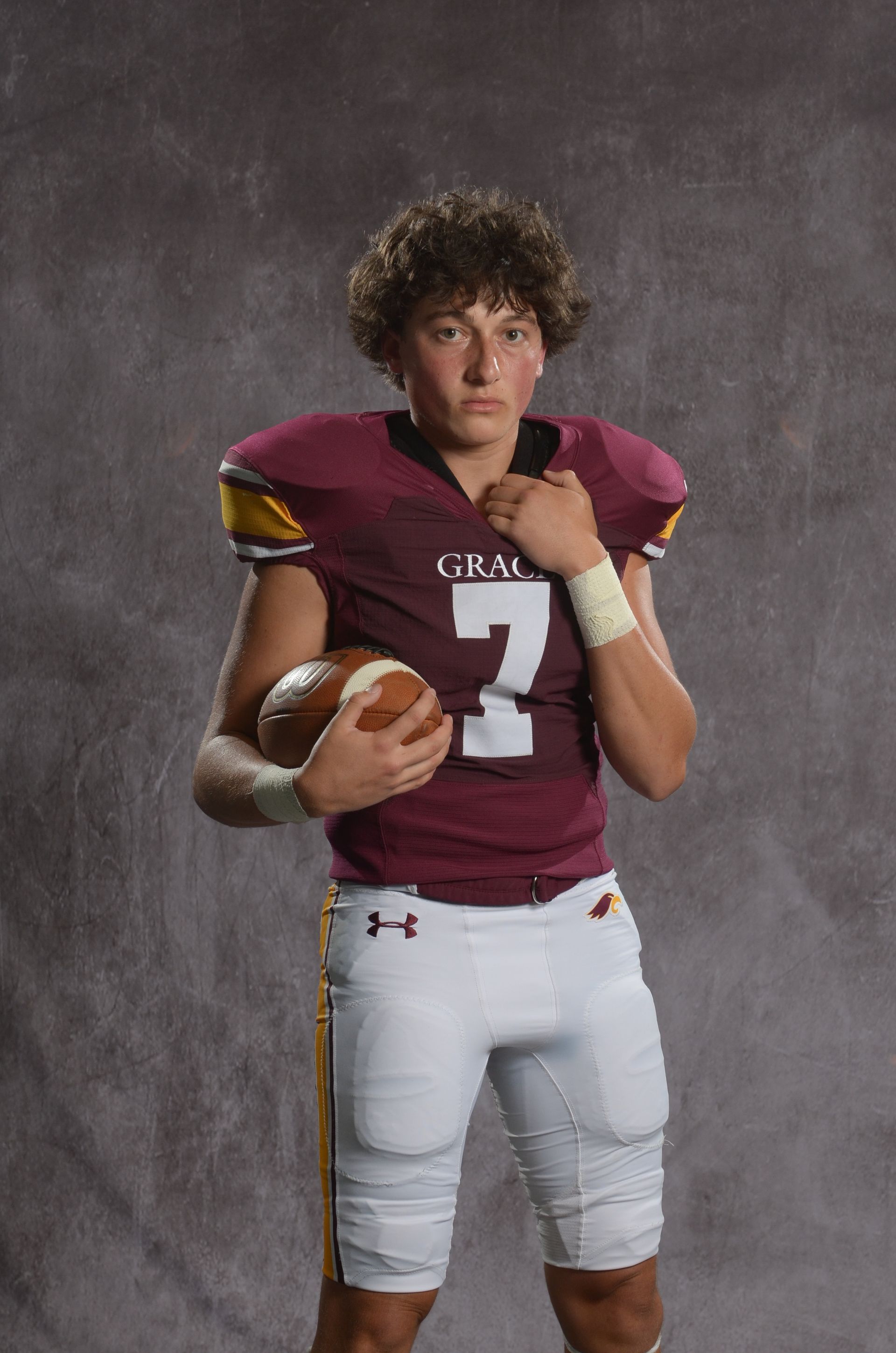 A maroon eagle head logo with a yellow beak on a white background.