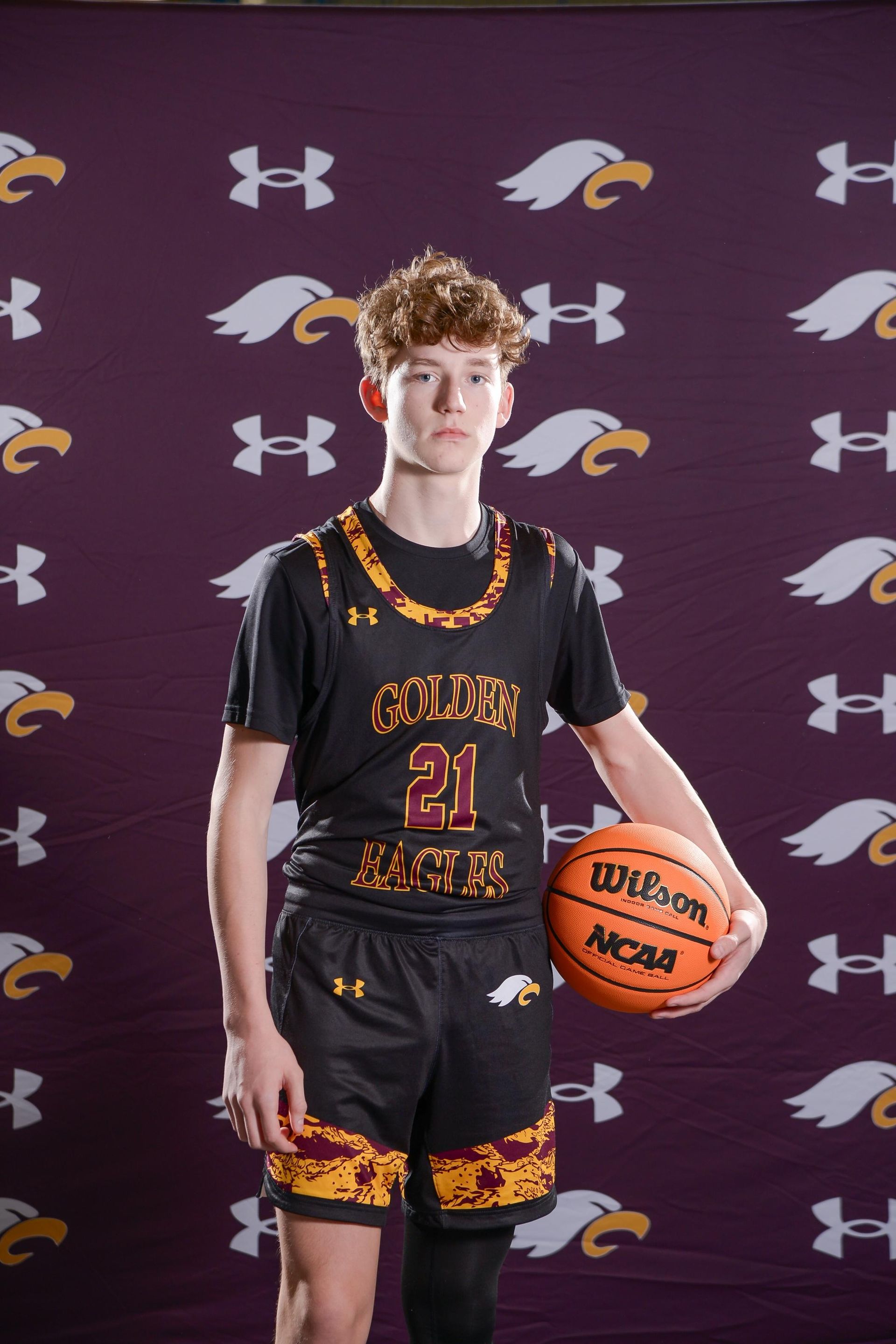 Basketball player spinning ball on finger, pointing forward, wearing Golden Eagles jersey.
