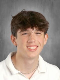 Teenage boy with brown hair smiles at the camera wearing a white polo shirt.