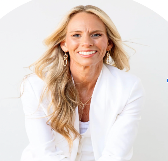 Woman with blonde hair, wearing white blazer and smiling.