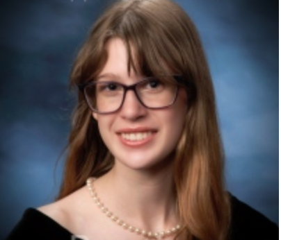 Woman with glasses and pearl necklace smiles; long light brown hair.