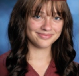 A young woman with brown hair and bangs smiles at the camera.