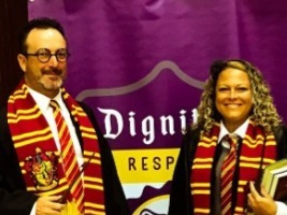 Two people wearing Gryffindor scarves and robes with a