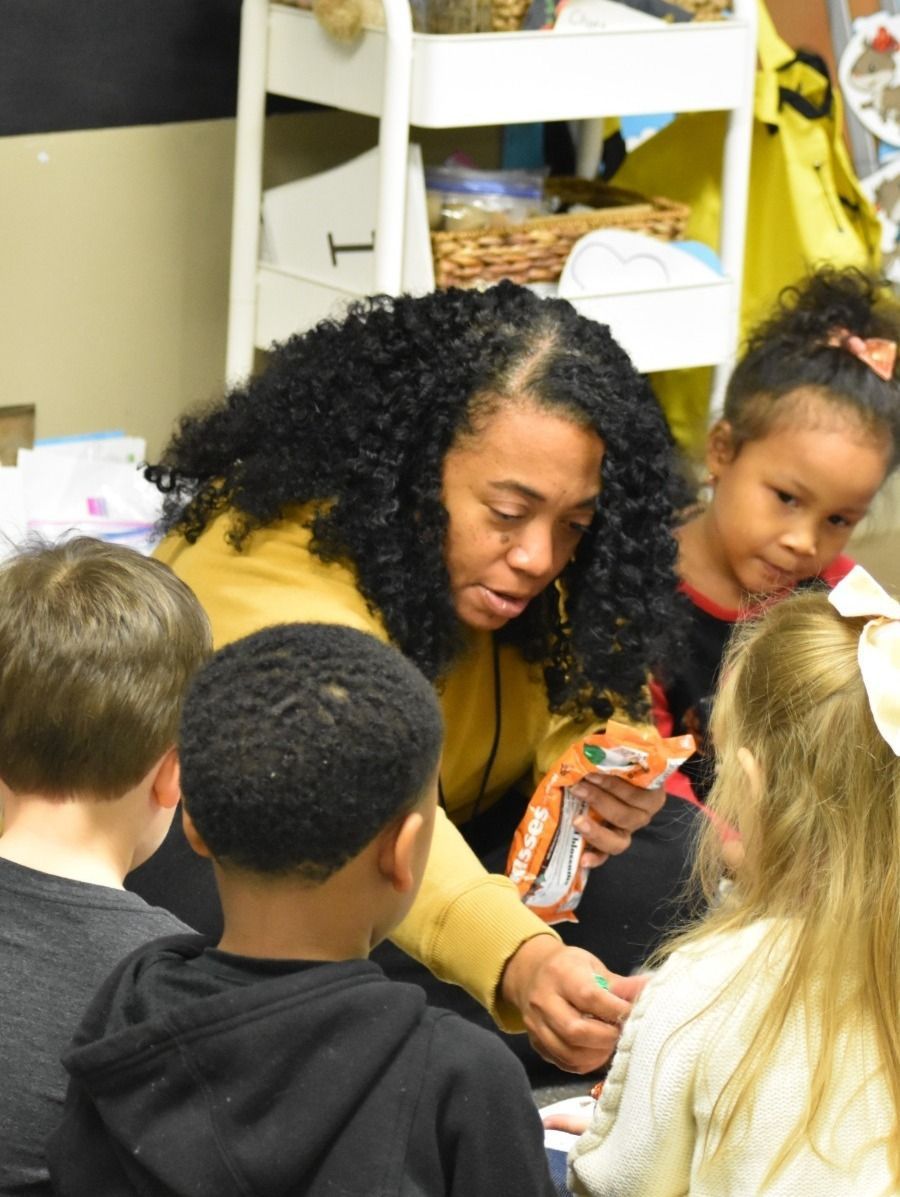 Teacher showing a toy to a group of young children in a classroom.