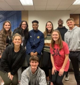 Group of diverse young adults smiling, posing indoors.