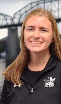 Blonde woman smiling at the camera, wearing black FCA jacket. Bridge in background.