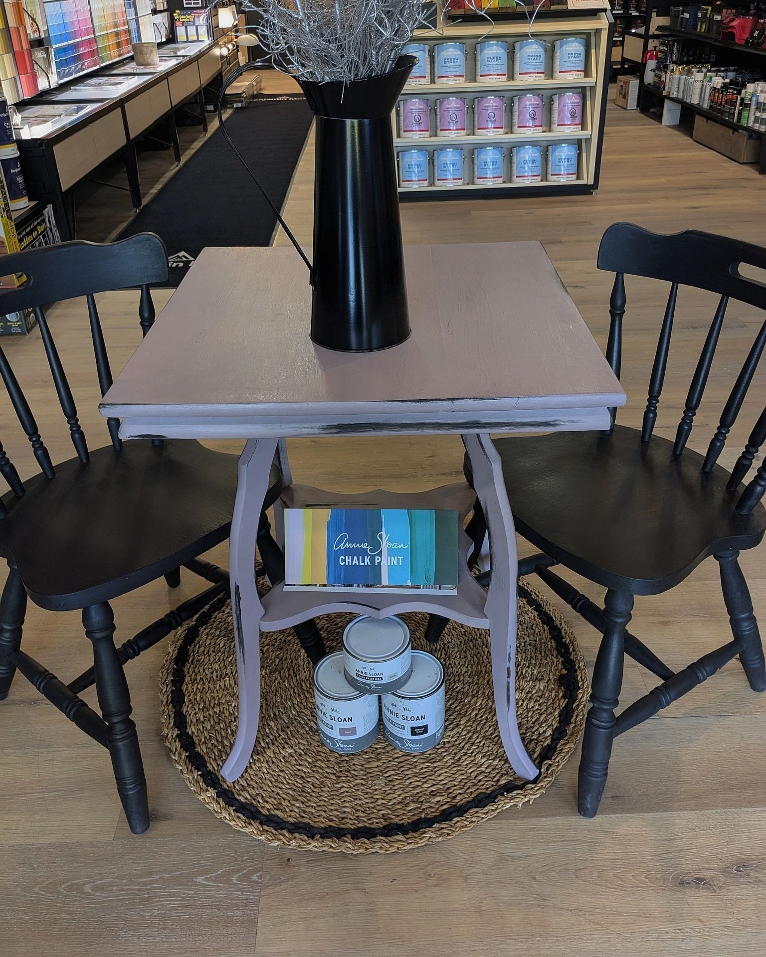 A table with two chairs and a vase on top of it in a store.