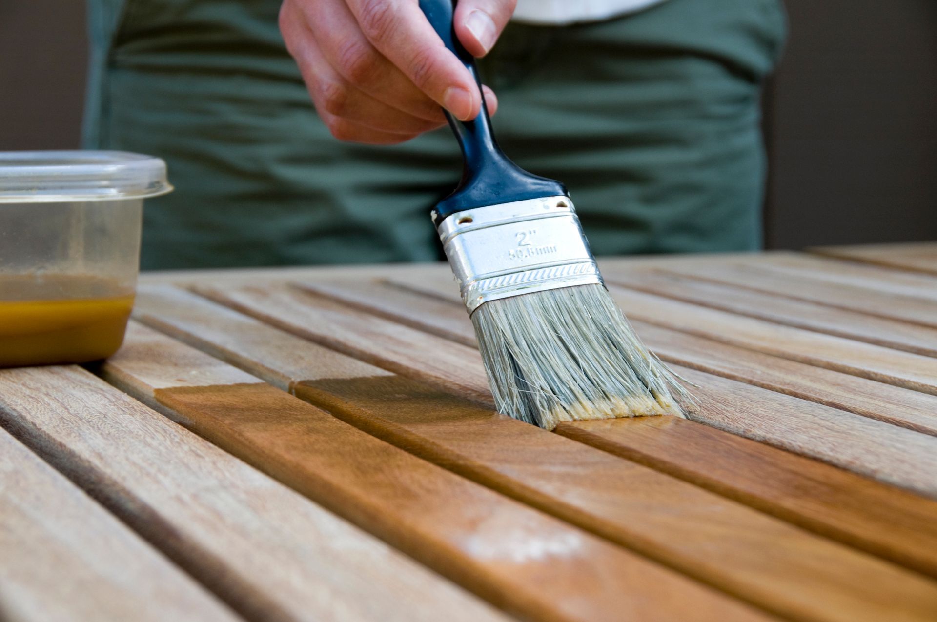 A person is painting a wooden table with a brush.