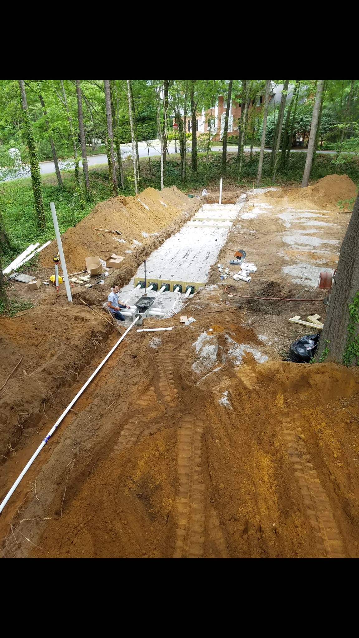 A large pile of dirt is being built in the middle of a forest.