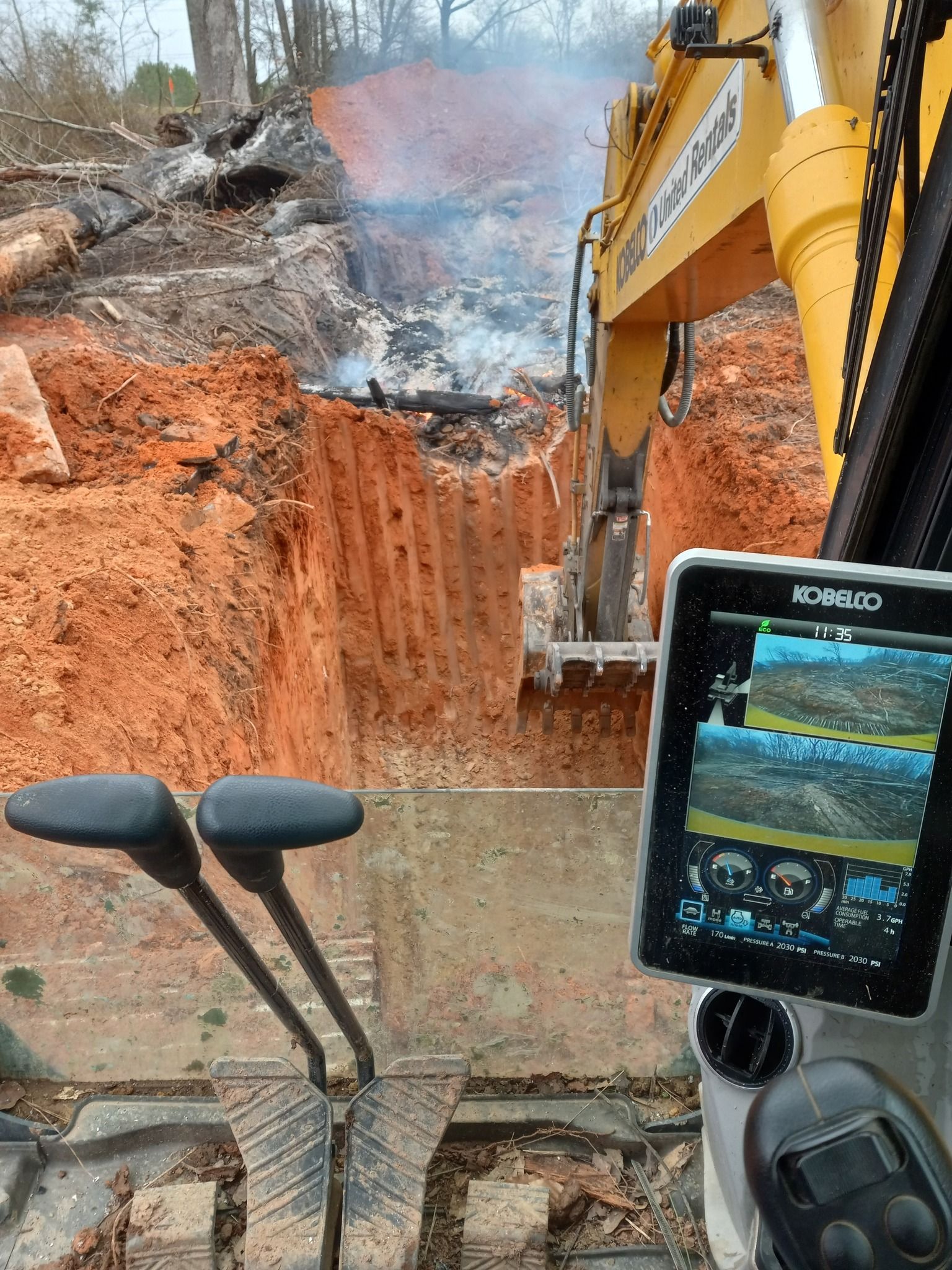 A yellow excavator is digging a hole in the ground.
