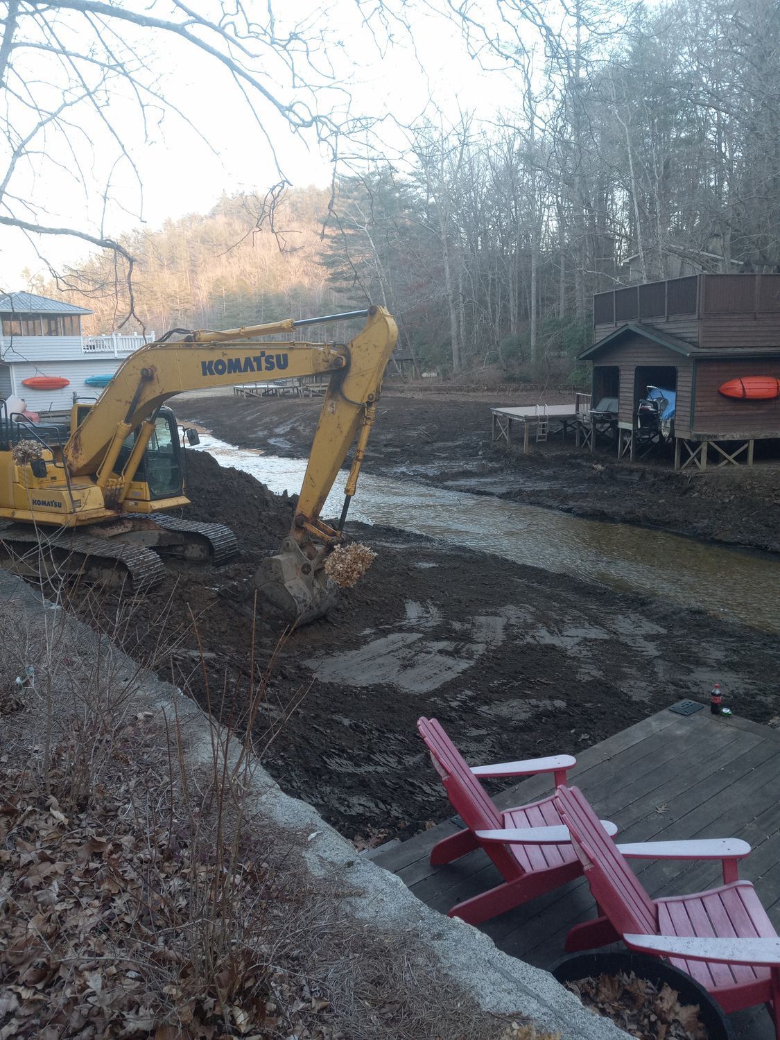 A yellow excavator is digging a hole in a river.