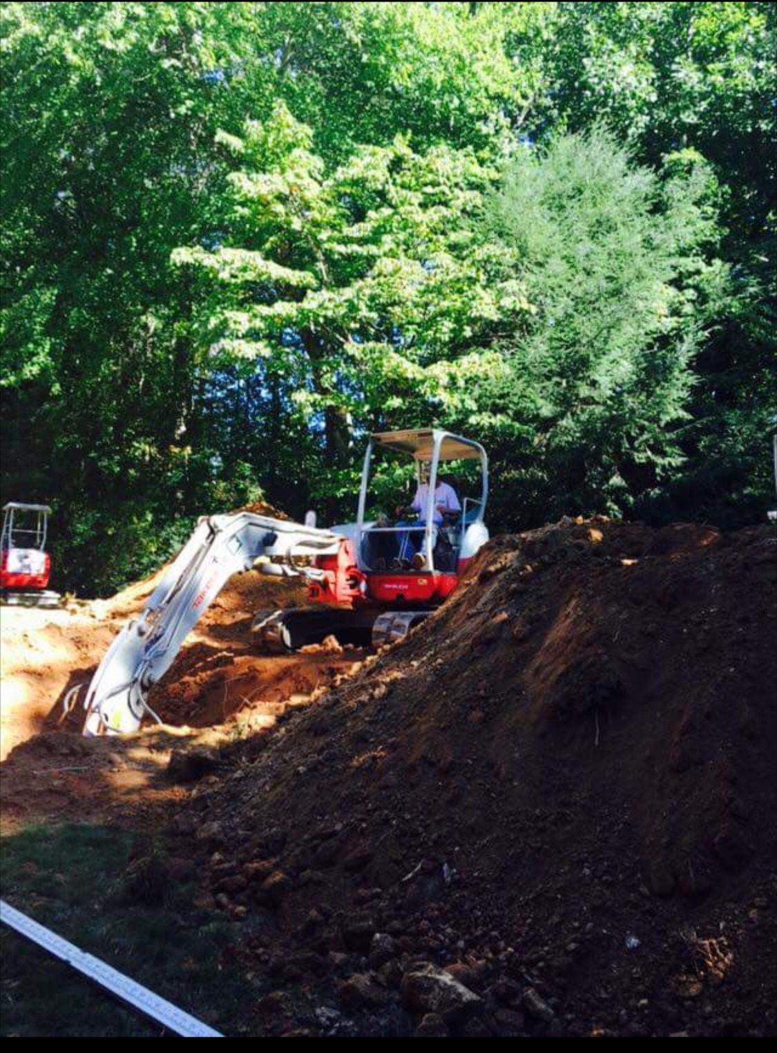 Two excavators are working on a pile of dirt.