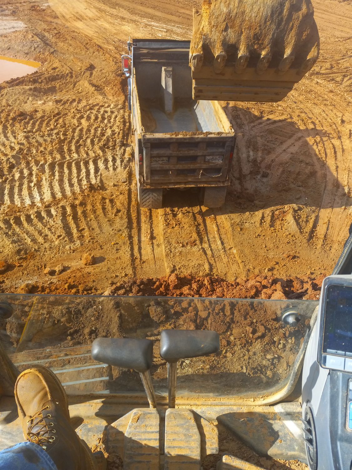 A bulldozer is loading dirt into a dump truck