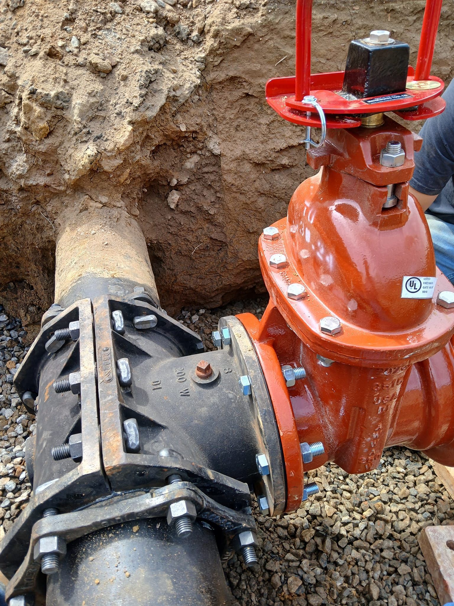 A man is working on a water pipe in the dirt.
