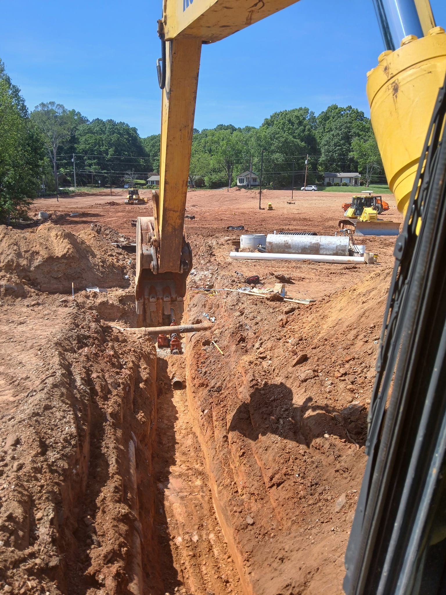 A yellow excavator is digging a hole in the dirt on a construction site.
