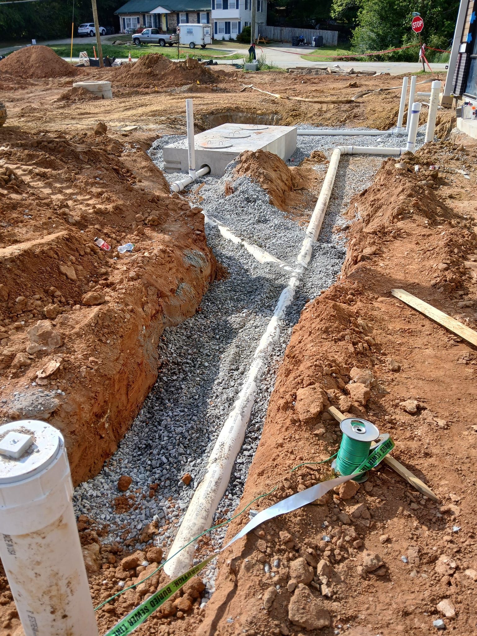 A drain pipe is being installed in the dirt on a construction site.