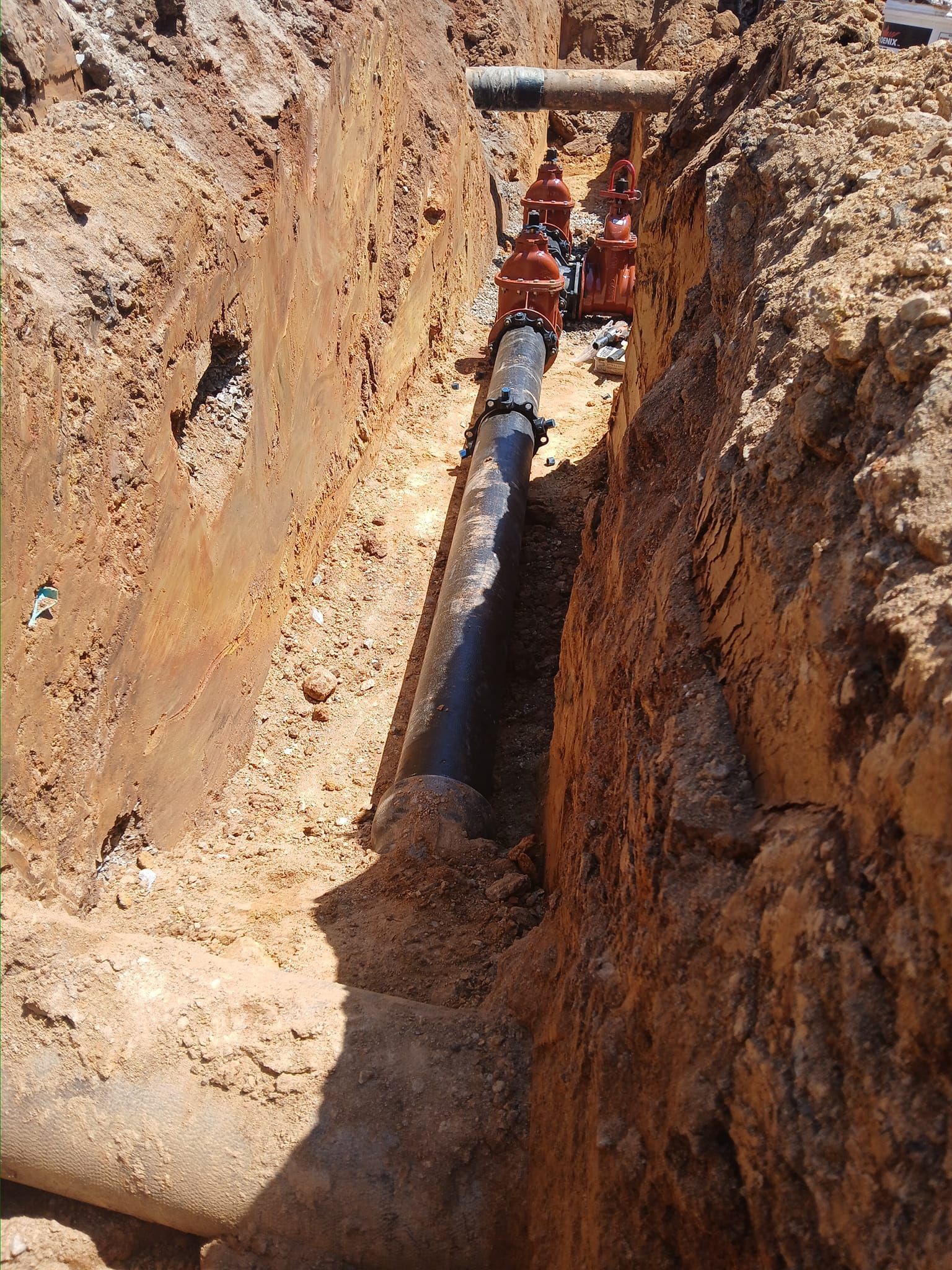 A pipe is being installed in a trench in the dirt.