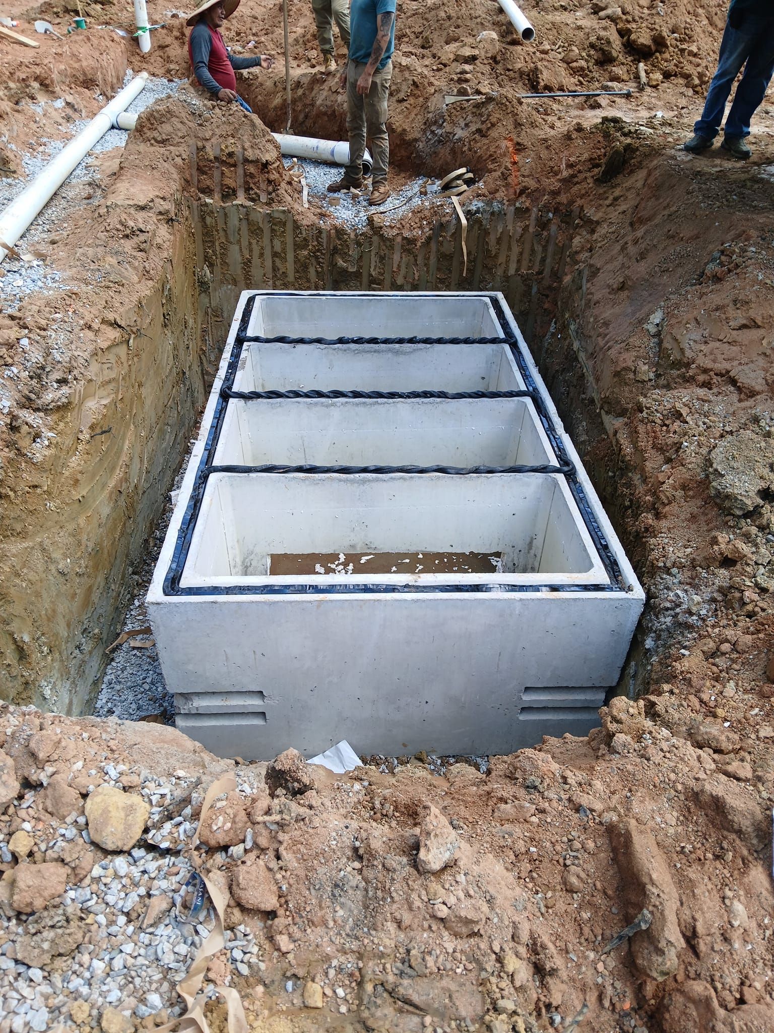 A concrete septic tank is being built in a hole in the ground.