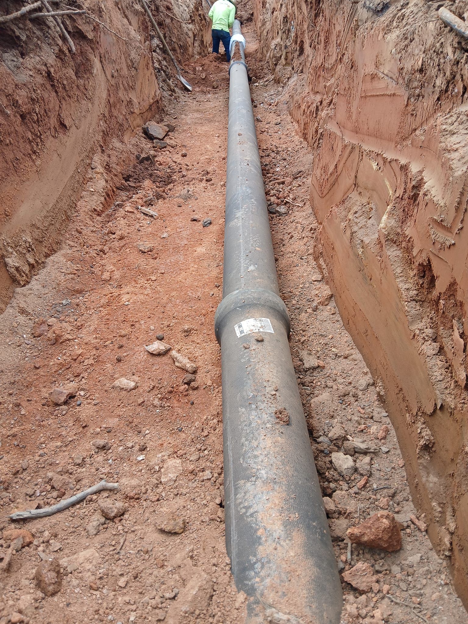 A man is standing next to a large pipe in the dirt.