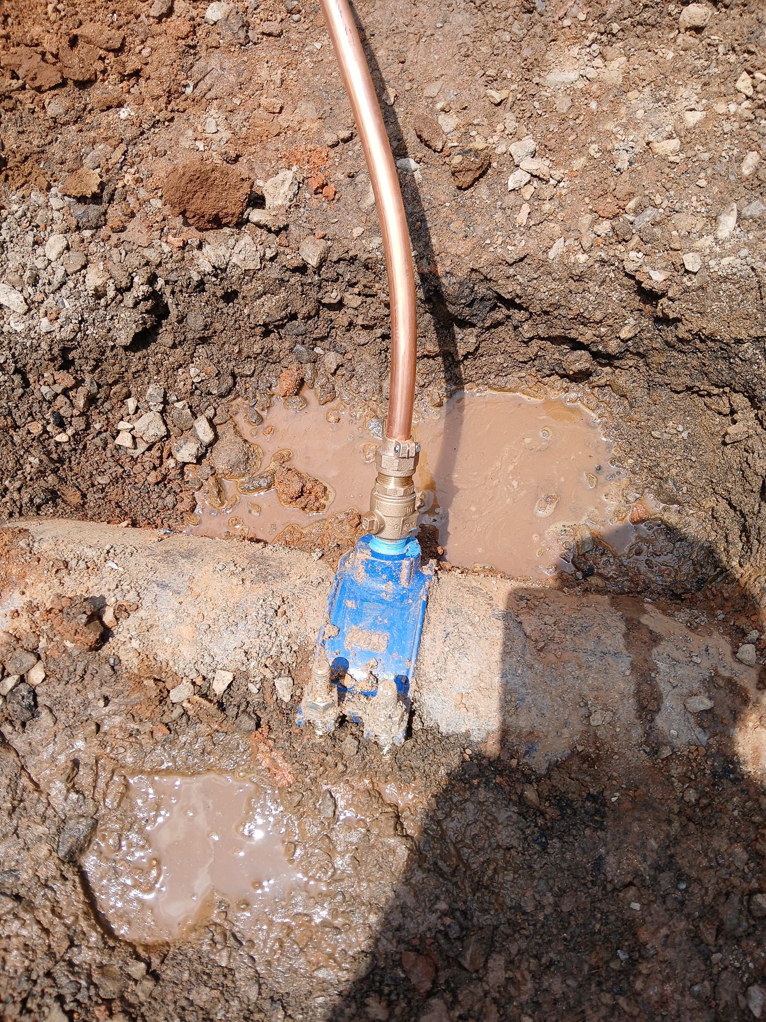 A copper pipe is connected to a water meter in the dirt.