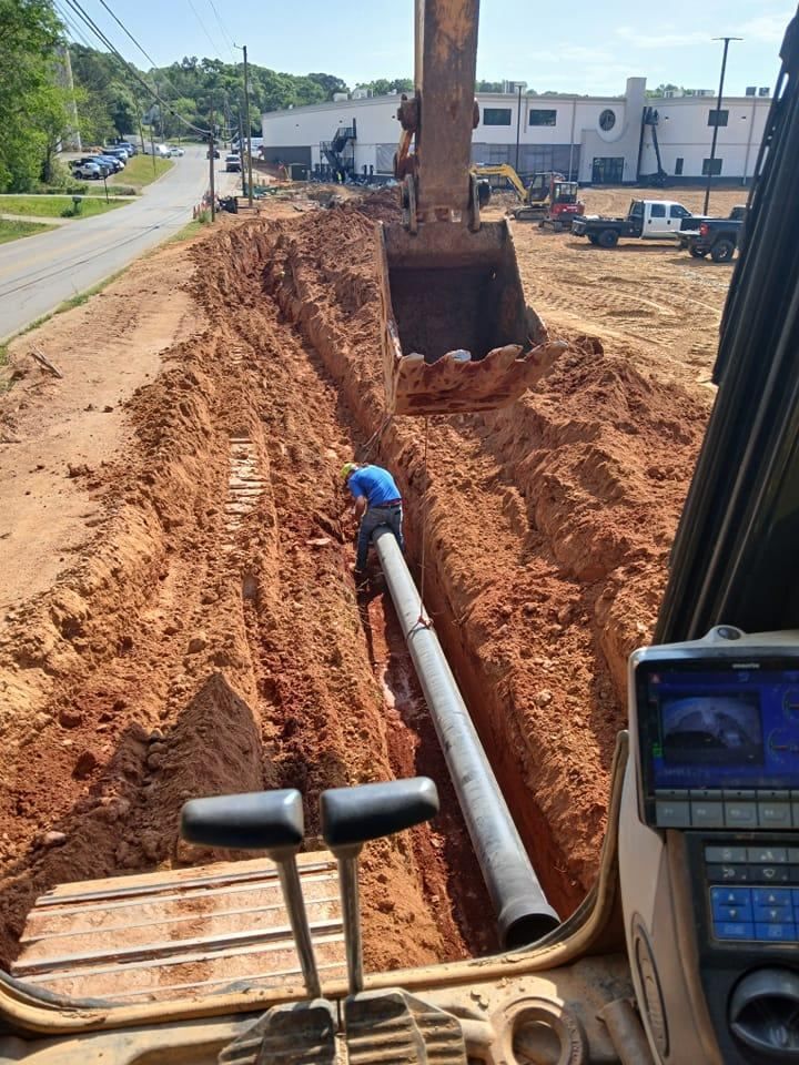 A bulldozer is digging a hole in the ground to install a pipe.