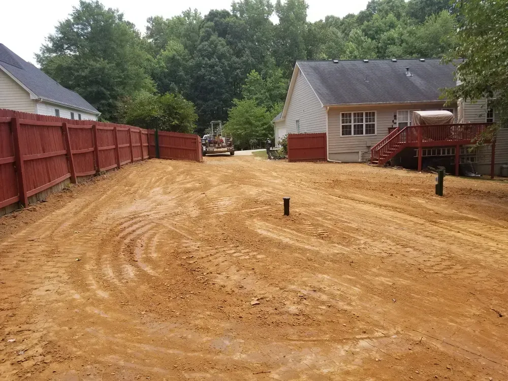 A dirt road leading to a house with a red fence