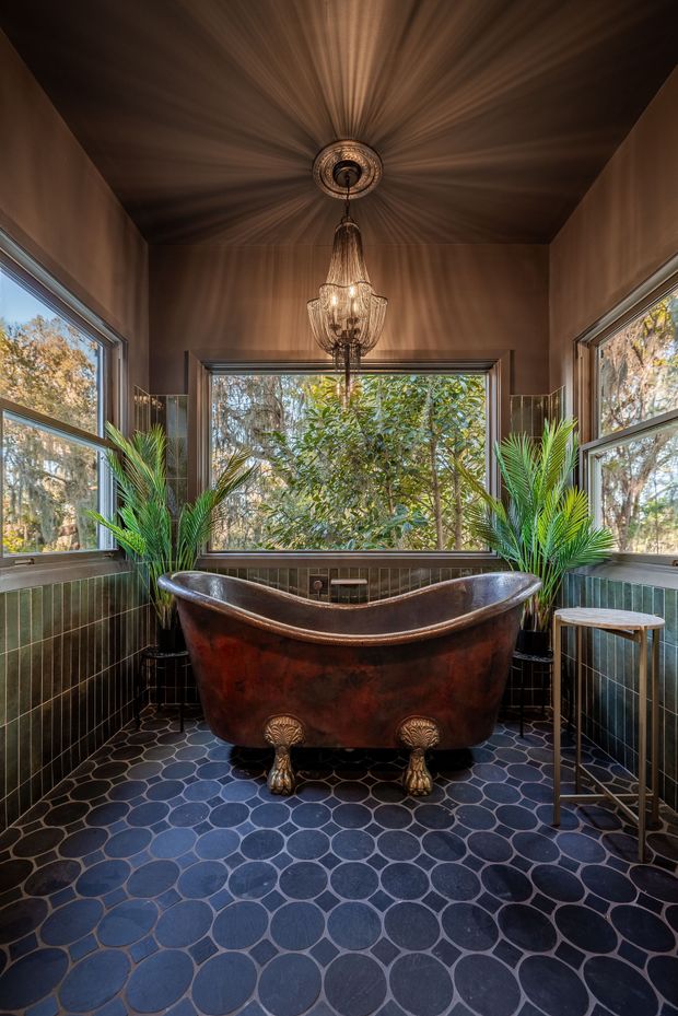 A bathroom with a copper bathtub and a chandelier hanging from the ceiling.