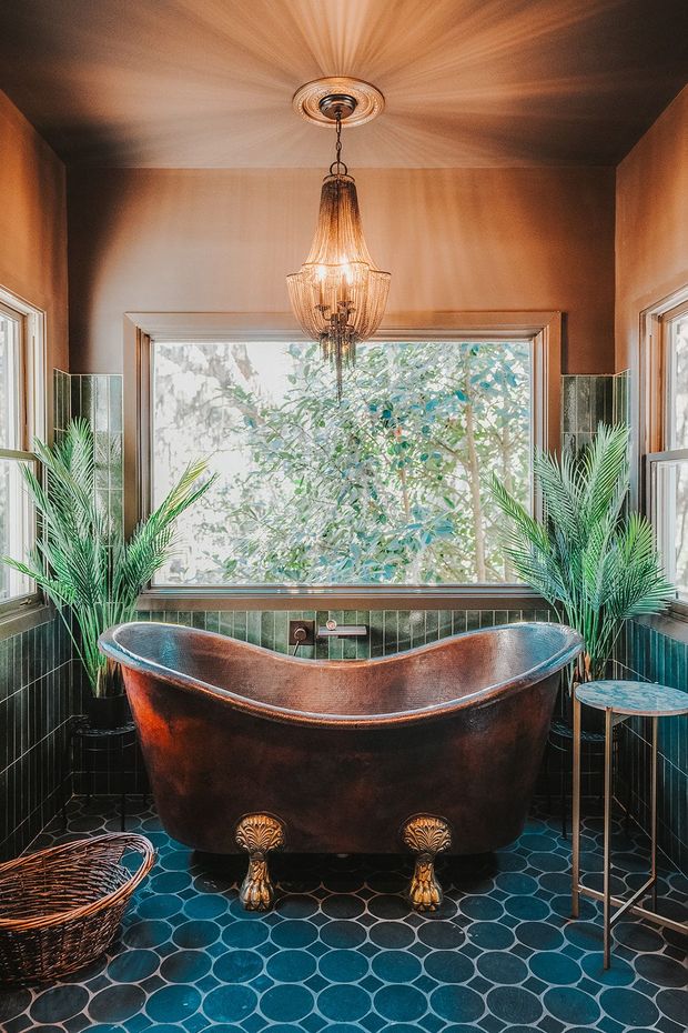 A bathroom with a copper bathtub and a chandelier hanging from the ceiling.