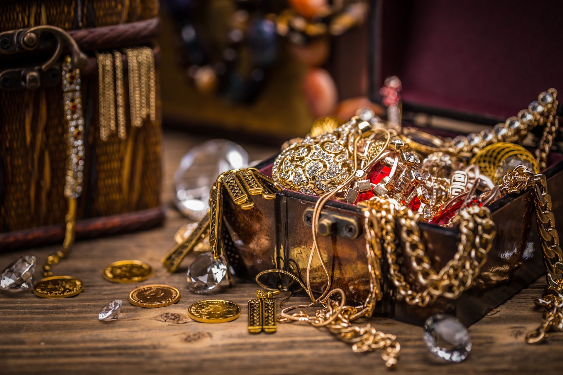 A treasure chest filled with gold jewelry on a wooden table.