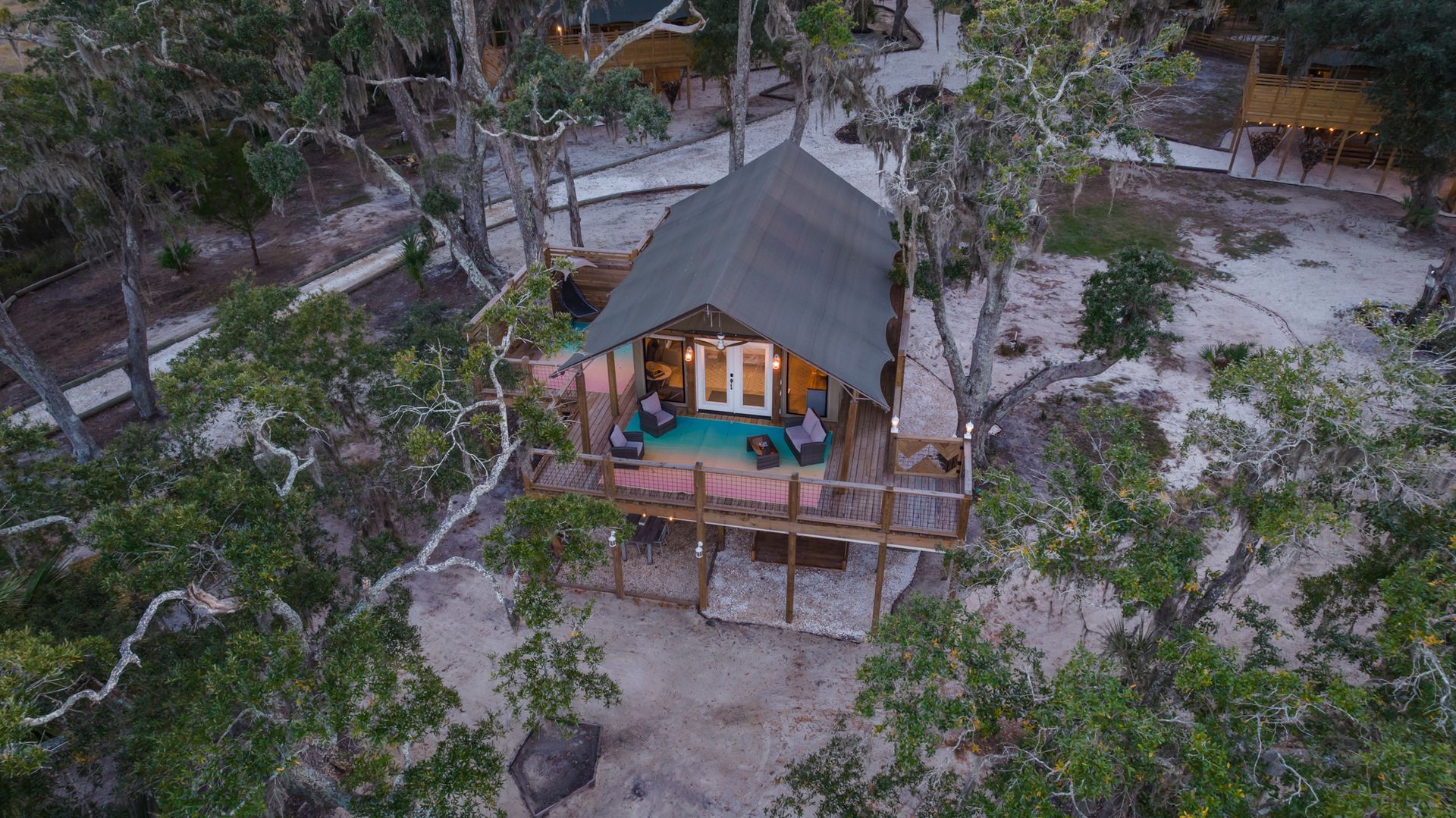 A treehouse with a deck and people sitting on it, surrounded by trees.